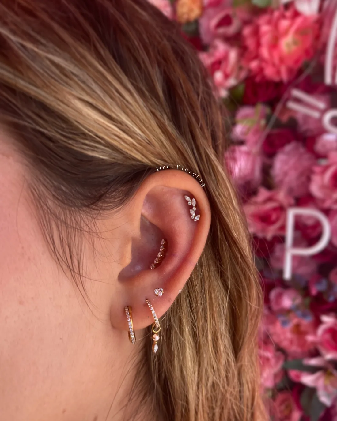 Orelha com composição de piercings em titânio — hélix, lóbulos e argolas — feita na Dra. Piercing